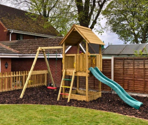 Wooden climbing frame with slide and swing built up in a backyard
