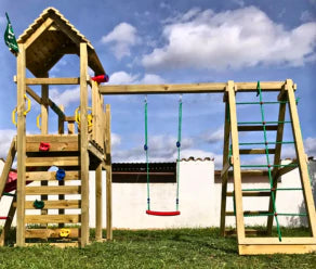 Wooden climbing frame with swing, climbing net, ladder and slide in a backyard