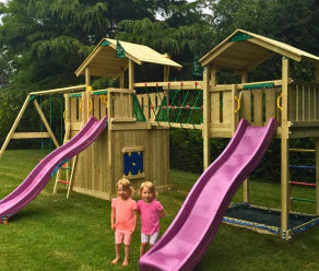 Wooden climbing frame with two slides, climbing net, net bridge and swings in a garden